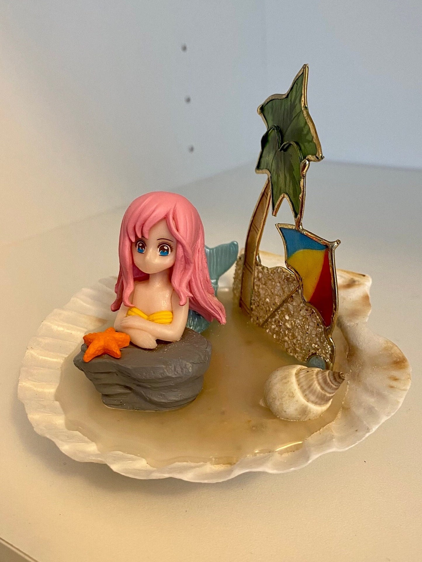 Mermaid on a shell beach with palm tree, shells, and umbrella pink hair