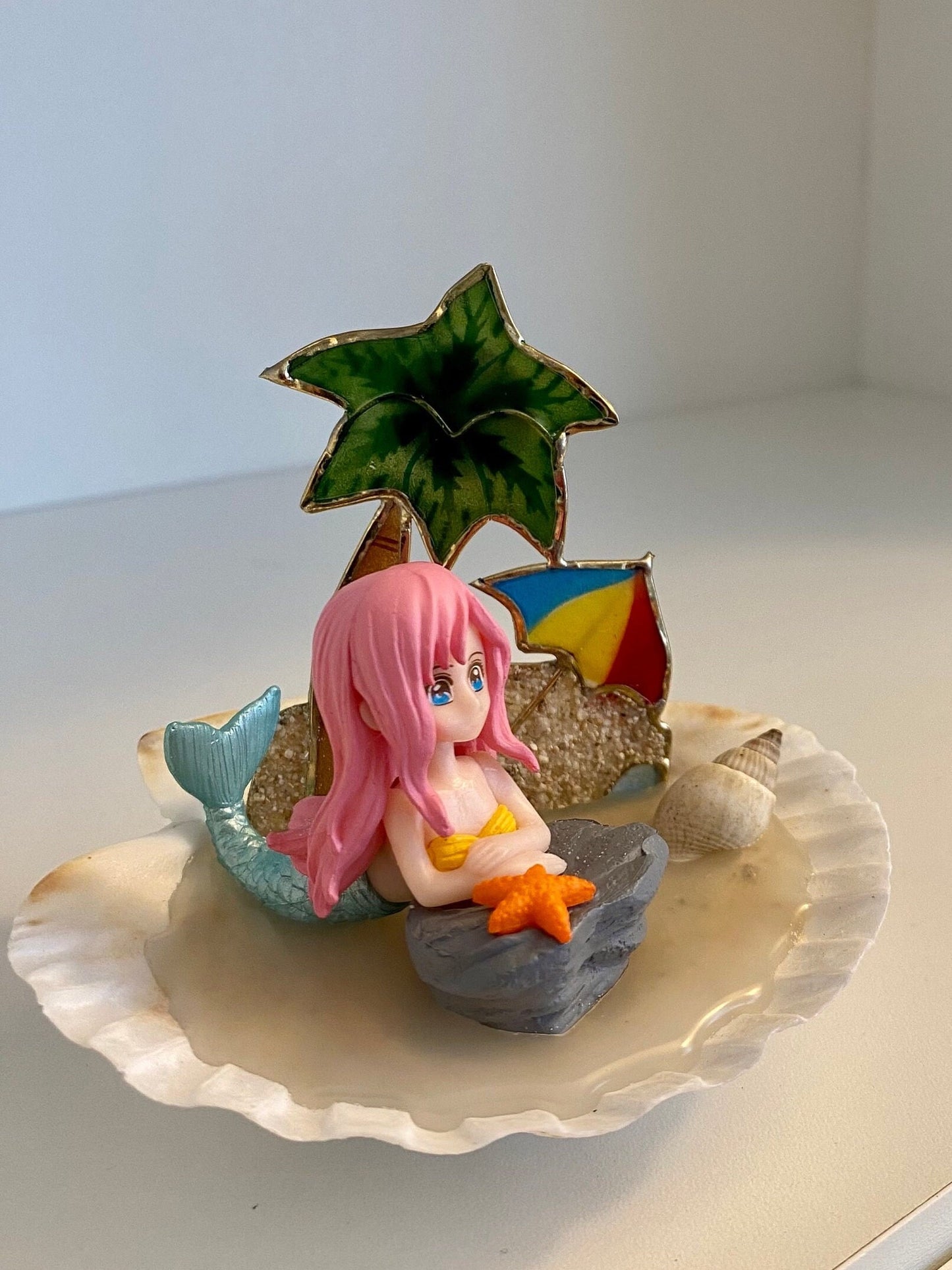 Mermaid on a shell beach with palm tree, shells, and umbrella pink hair